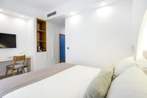 a white bedroom with a bed and a desk at Euphoria Boutique Hotel in Chrysi Ammoudia