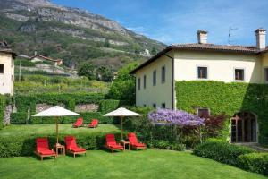 a garden with chairs and umbrellas in front of a building at Relais Palazzo Lodron in Rovereto