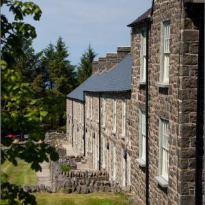 an old stone building with white windows on it at Nant Gwrtheyrn in Llithfaen +43 photos