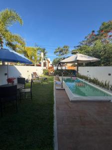 a swimming pool with umbrellas and tables and chairs at Casa 4 suítes com piscina Condomínio Lagoa Dourada Ilha de Itaparica BA in Vera Cruz de Itaparica