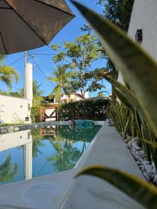 a pool with an umbrella next to a building at Casa 4 suítes com piscina Condomínio Lagoa Dourada Ilha de Itaparica BA in Vera Cruz de Itaparica