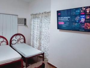 a room with two beds and a tv on the wall at pousada benção in Aparecida