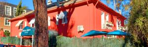 a red building with blue umbrellas in front of it at C&H Aravaca Garden in Madrid