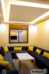 a living room with a blue couch and yellow pillows at Maghrib ARABI OULED OUJIH in Kenitra