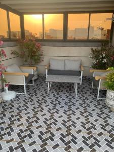 a patio with two benches on a checkered floor at Maghrib ARABI OULED OUJIH in Kenitra