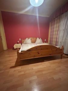 a bedroom with a wooden bed with a red wall at Gasthof Vogelleitner in Sankt Aegyd am Neuwalde