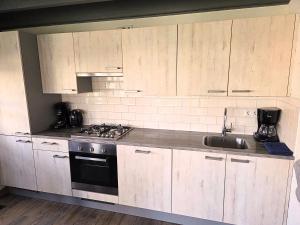 a kitchen with wooden cabinets and a sink and a stove at Zeeuwse Luwte in Stavenisse