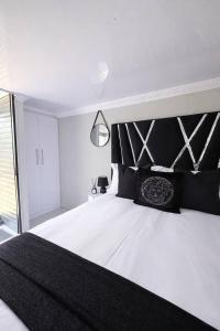 a bedroom with a large bed with a black headboard at Elite Luxe Cabin Suite in Welkom