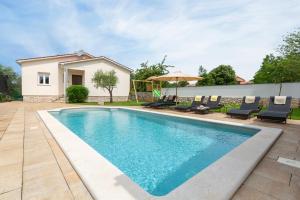 a swimming pool with chairs and a house at Villa Luka Nedešćina in Nedeščina