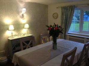 a dining room with a table with a vase of flowers on it at Birtles Farm Bed and Breakfast in Knutsford