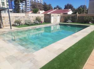 a swimming pool with blue water and green grass at Villa Sol in Roquetas de Mar