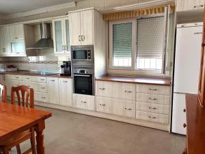 a kitchen with white cabinets and a table and a refrigerator at Villa Sol in Roquetas de Mar