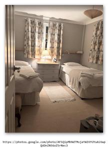a bedroom with two beds and a window with curtains at Silver Lodge Guest House in Mildenhall