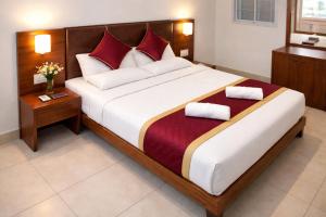 a bedroom with a large bed with red pillows at DJ Palace and Residency in Tiruvannāmalai