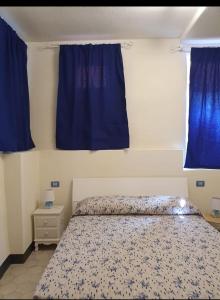 a bedroom with two blue curtains and a bed at Il Nuovo Vecchio Frantoio di Gardan Con Piscina in Vignana