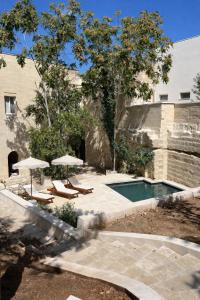 a swimming pool with two umbrellas and two lounge chairs at CAVA Urban Relais & Pool in Lecce