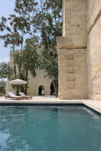 a swimming pool with two lounge chairs and a building at CAVA Urban Relais & Pool in Lecce