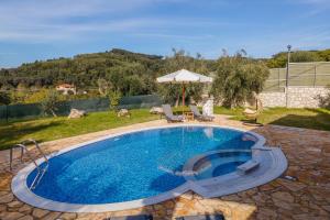 a swimming pool in a yard with a umbrella at Villa Dias by Elayan Villas Corfu in Karousádes
