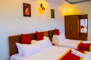 a bedroom with two beds with red and white pillows at DJ Palace and Residency in Tiruvannāmalai