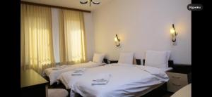 two beds in a hotel room with white sheets at Златоград in Zlatograd