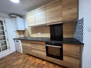 a kitchen with wooden cabinets and a black counter top at Maison en face du Marche Notre-Dame in Poitiers