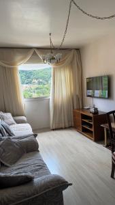 a living room with two beds and a television at Ap Centro - Wi-fi, Piscina, com Vista da Praça in Águas de Lindoia