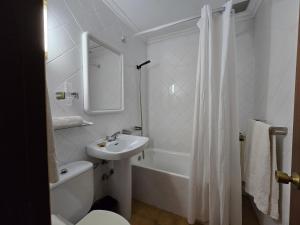 a white bathroom with a sink and a toilet and a tub at Pensión La Unión in Trevías