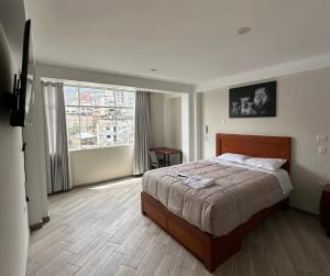 a bedroom with a large bed and a large window at Hotel Altavista in Abancay