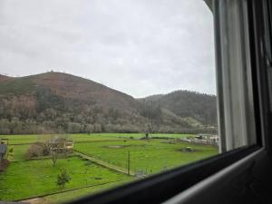 a window with a view of a field and mountains at Pensión La Unión in Trevías +9 photos