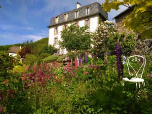 a garden with flowers and a white bench in front of a building at La Maison de Jeanne, maison d'hôtes in Thiézac