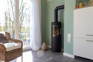 a fireplace in a living room with a chair and a window at Ferienhaus Clara in Wardenburg +27 photos