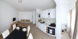 a kitchen with white cabinets and a black table at Avenida Dr Baltazar Lopes da Silva 33A in Mindelo