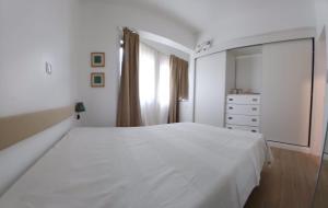 a white bedroom with a large bed and a dresser at Avenida Dr Baltazar Lopes da Silva 33A in Mindelo