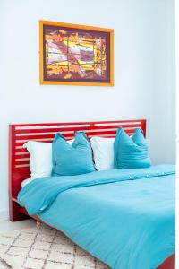 a large bed with blue sheets and pillows at The Bacongo Gem in Brazzaville