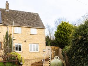 a brick house with a fence and stairs in front of it at White Stones in Burford