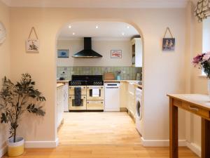 a kitchen with an archway leading into a kitchen with white appliances at White Stones in Burford
