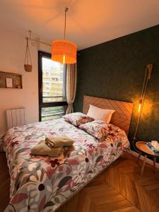a bedroom with a bed with a comforter and a window at Les Chambres de David in Paris