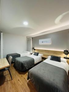 a hotel room with three beds and a table at Hotel La Bonaigua in Vielha