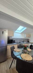a kitchen with a table with chairs and a refrigerator at Au calme, parking gratuit,proche centre Thonon les bains in Allinges