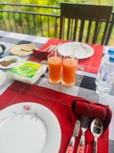 a table with plates and glasses of orange juice at Sigiriya Yahana in Sigiriya