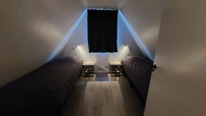an attic room with two beds and a window at Gramsbergs Huuske in Gramsbergen +33 photos