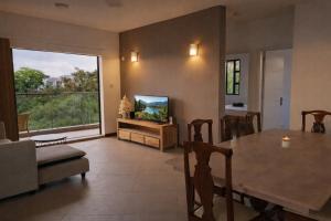 a living room with a table and a large window at Sunset Haven in Flic-en-Flac