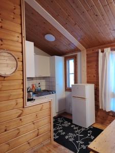 a small kitchen with a refrigerator in a wooden cabin at Riihitupa 10 in Muurame