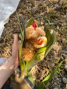 a person holding a plate of food on the ground at La Capanna Sumatra Ecovillage in Timbanglawang