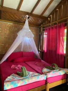 a bedroom with two beds with a mosquito net at La Capanna Sumatra Ecovillage in Timbanglawang