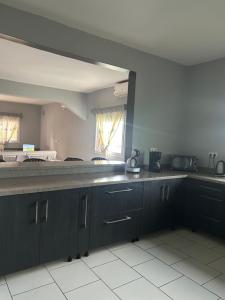 a kitchen with black cabinets and a white tile floor at Le Donjon du lycée in Sada +4 photos