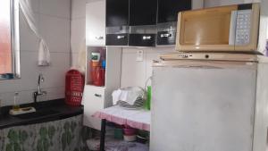 a microwave on top of a refrigerator in a kitchen at Casa de adao in Guarujá