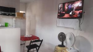 a kitchen with a tv on a wall with a fan at Casa de adao in Guarujá
