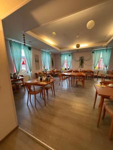 a restaurant with wooden tables and chairs and windows at Rathaushotel in Eibenstock