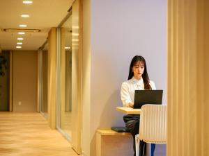 a woman sitting at a desk with a laptop at hotel miura kaen in Takikawa